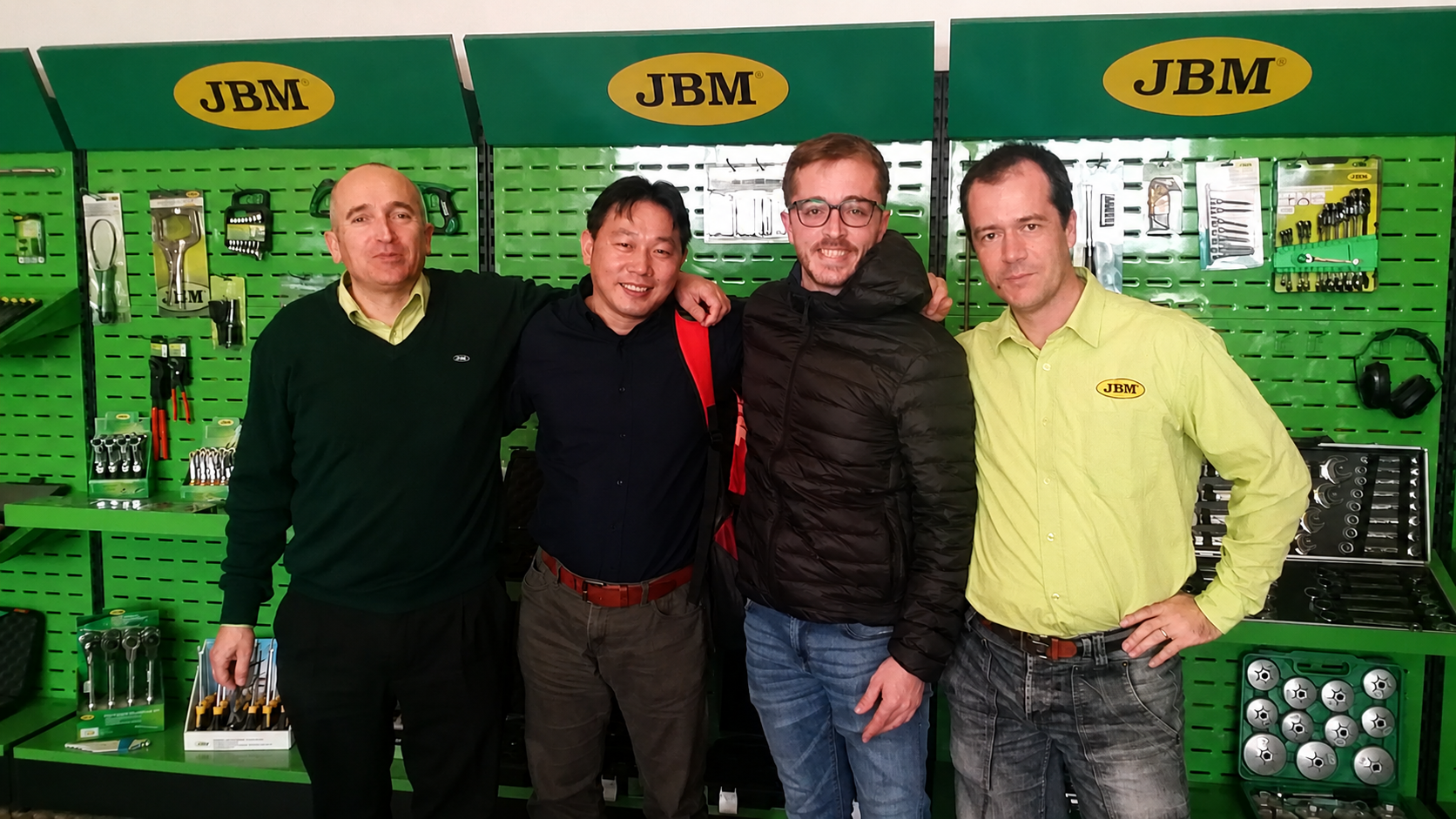 Four tool-industry professionals during a market visit in front of professional tool displays